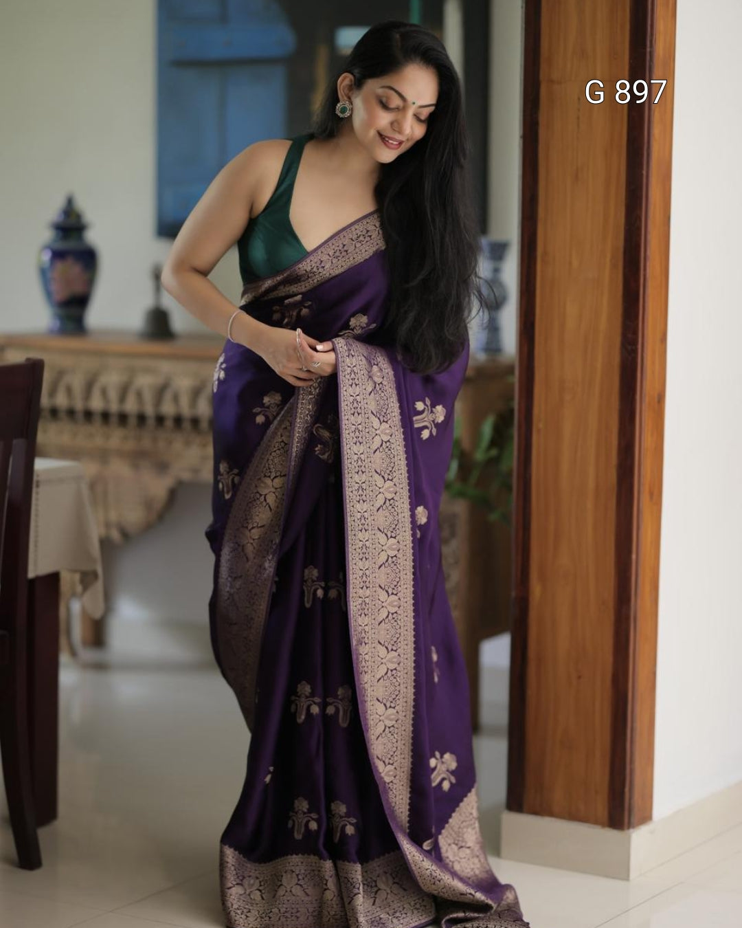 Woman wearing a purple saree with gold patterns indoors