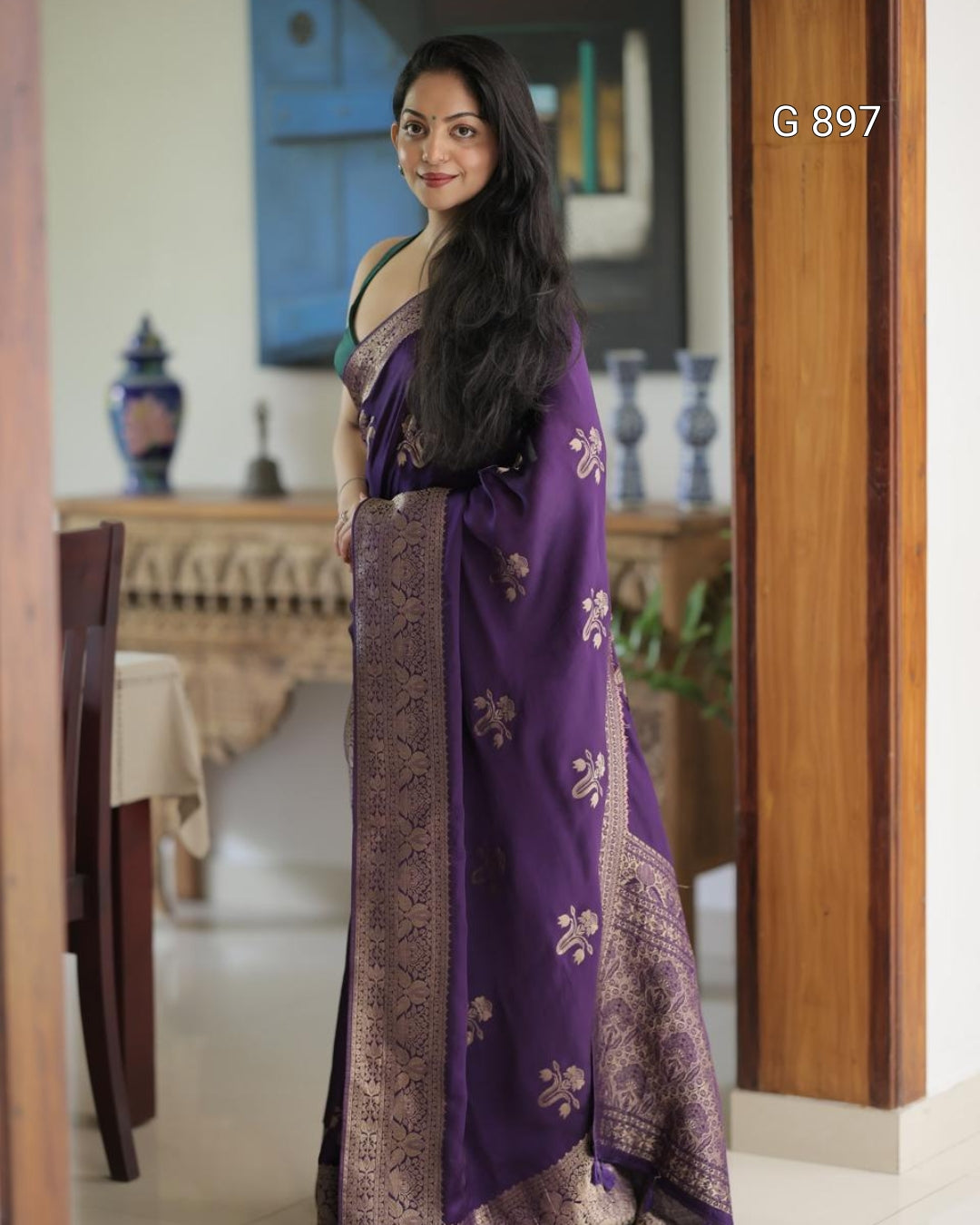 Woman wearing a purple saree with a pattern in a room setting