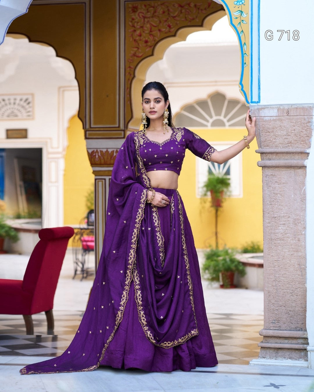 Woman in a purple traditional outfit standing in an ornate architectural setting.