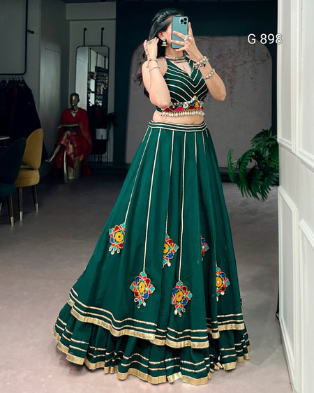 Person wearing a green embroidered traditional outfit in a room.