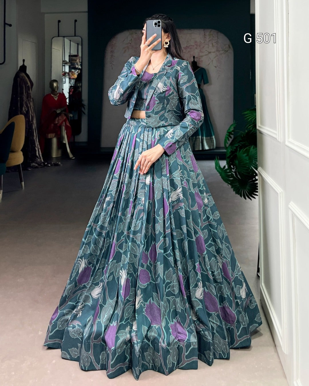 Woman wearing a long, floral-patterned dress in a room with mirrors and a plant.