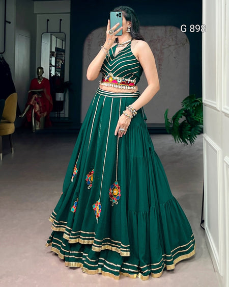 Woman wearing a green embroidered dress taking a mirror selfie.